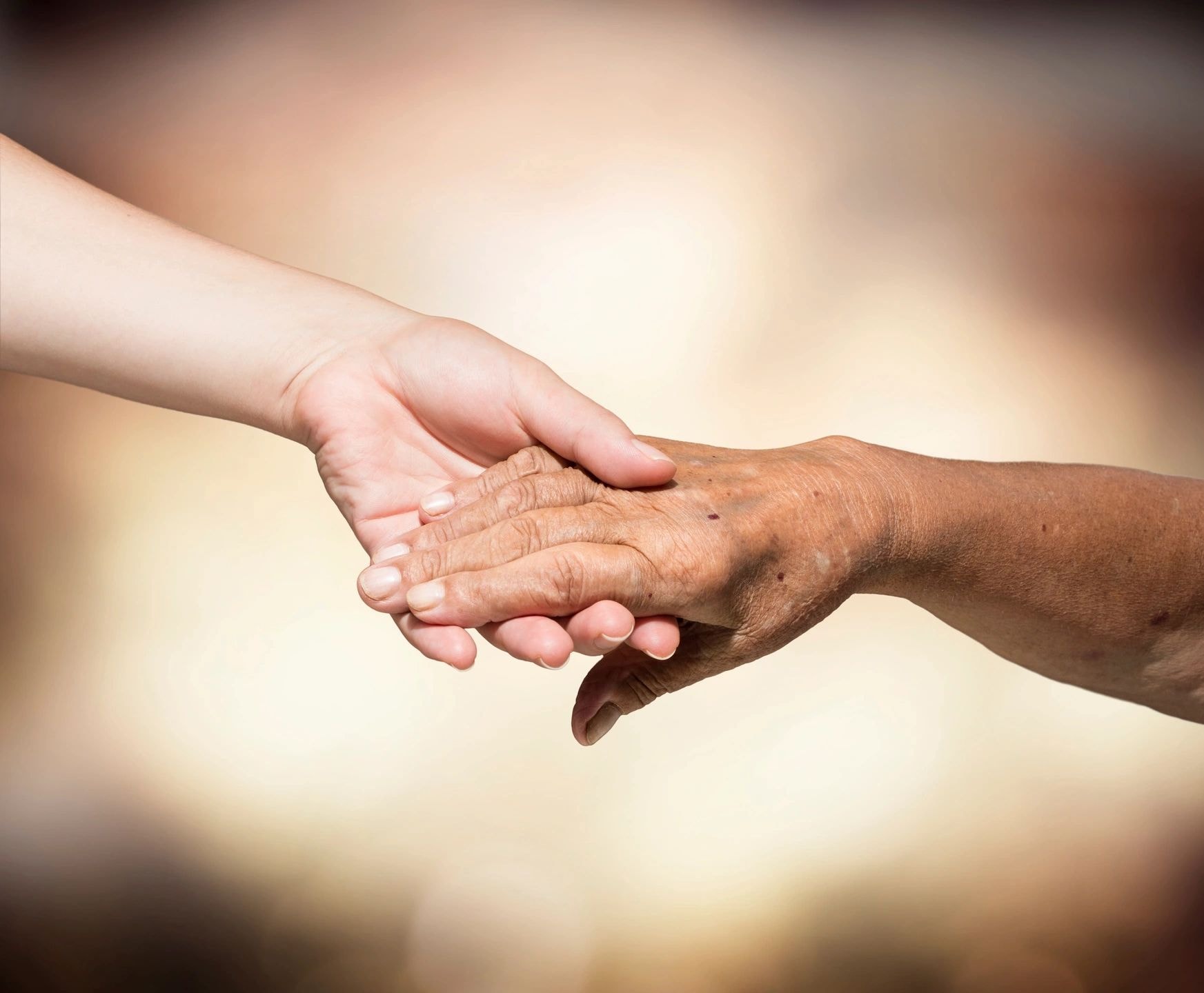 Caregiver holding senior resident hands compassionately